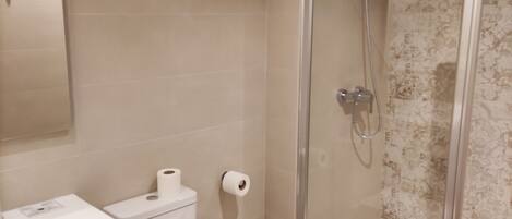 A bathroom with a toilet, a sink, and a shower with a glass door.
