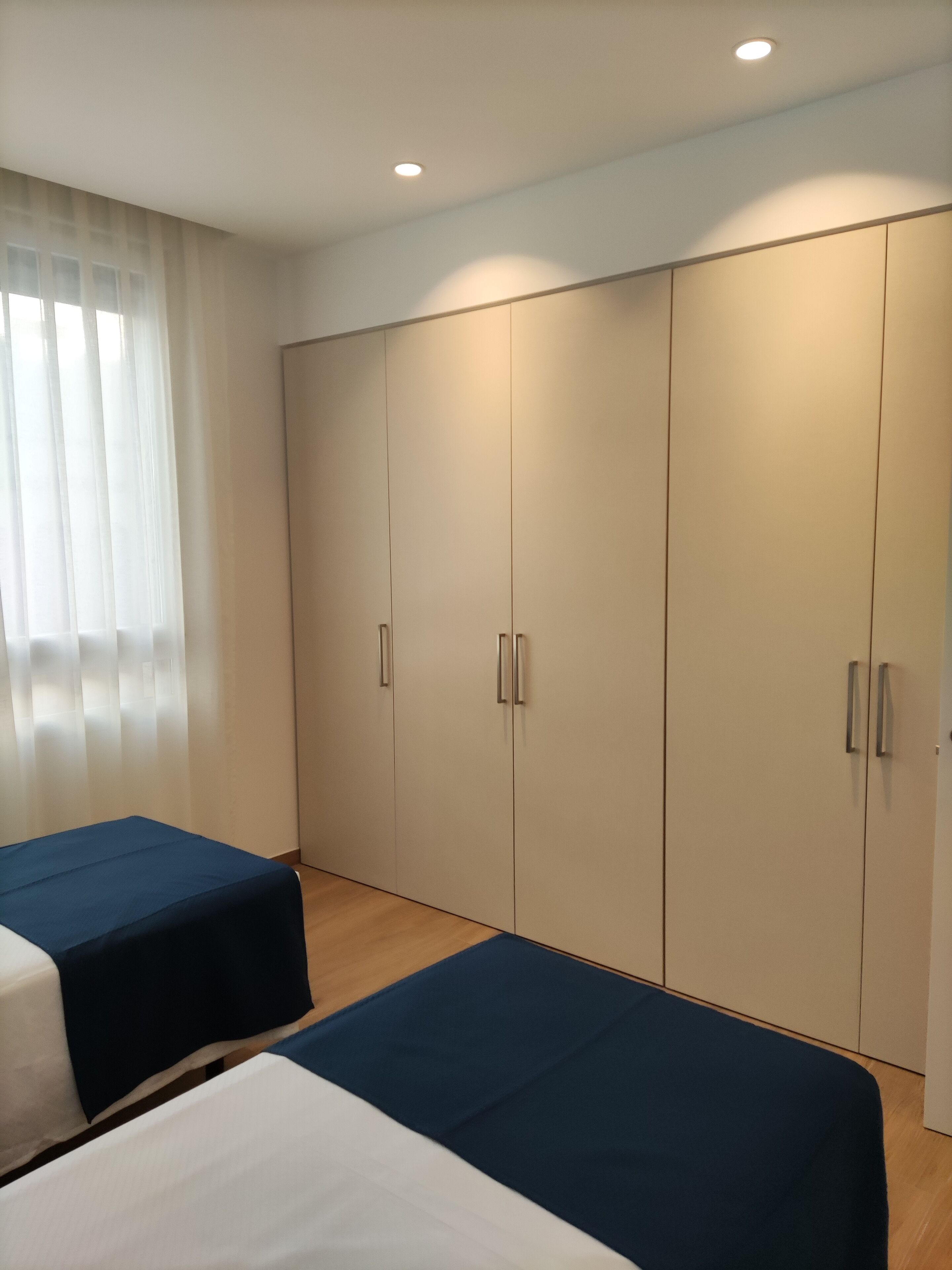 Une chambre avec deux lits, une grande armoire et une fenêtre avec des rideaux.