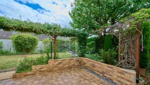 Un patio con muro de ladrillo y pérgola.