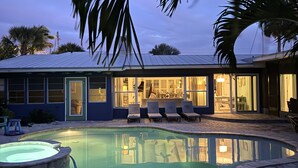 Uma casa com piscina, espreguiçadeiras e um espaço de estar ao ar livre.