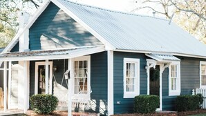 A single-story house with a gabled roof, a porch with a swing, and a small front yard. - Cozy Millbrook Cottage | Pool Access Near Capitol (Millbrook)