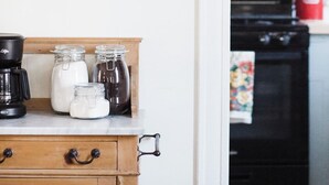 A kitchen with a coffee maker, jars, a teapot, and a vase with dried flowers on a shelf. - Cozy Millbrook Cottage | Pool Access Near Capitol (Millbrook)