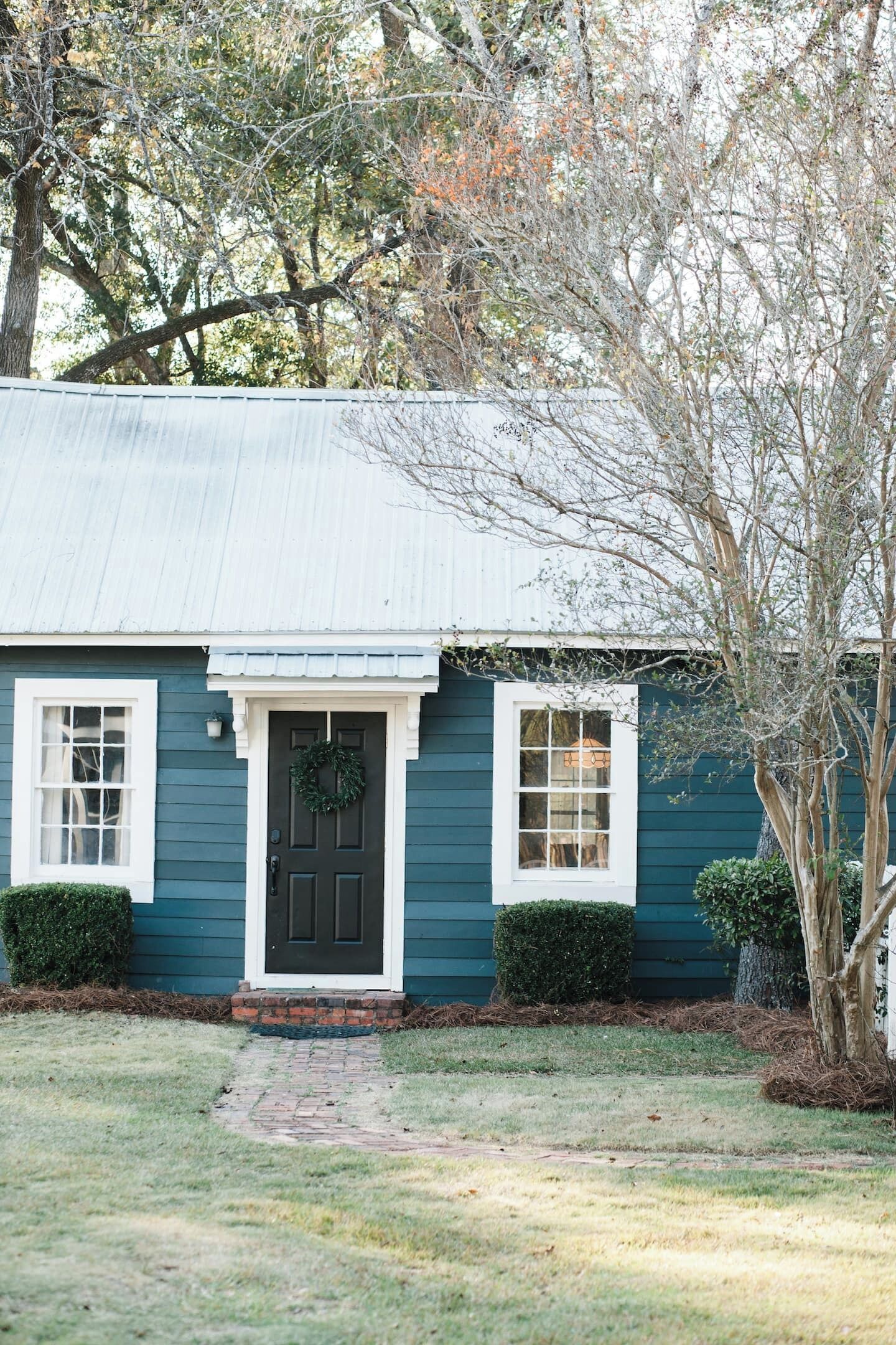 Una casa con fachada azul oscuro, una puerta principal negra y un pequeño porche.