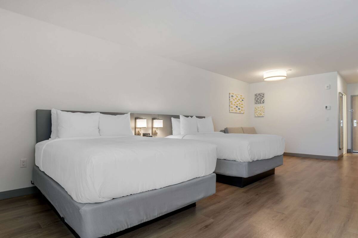 Une chambre d’hôtel avec deux lits, un plancher en bois et un design moderne.