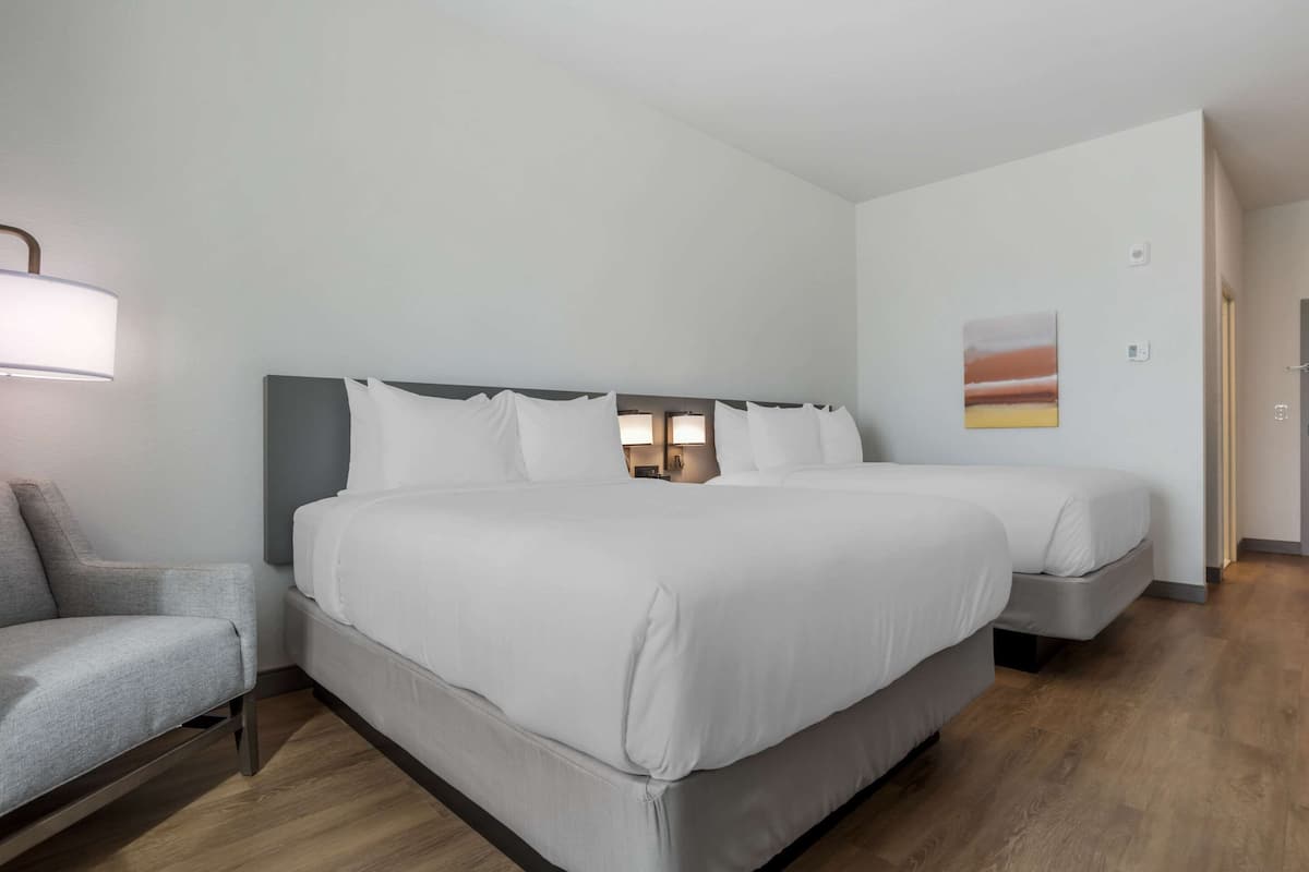 Une chambre d’hôtel avec un grand lit, une table de chevet, une lampe et un tableau au mur.