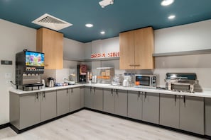 A modern kitchen with a coffee machine, microwave, and a digital screen displaying a fruit juice advertisement. - Comfort Inn & Suites Panama City Beach - Pier Park Area (Panama City Beach)