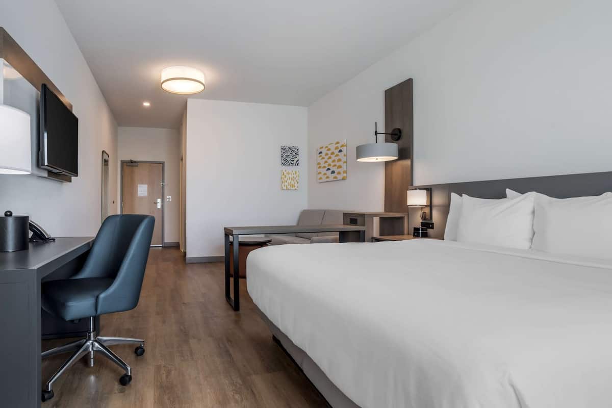 Une chambre d’hôtel moderne équipée d’un grand lit, d’un bureau avec une chaise, d’une télévision et d’une lampe de bureau.