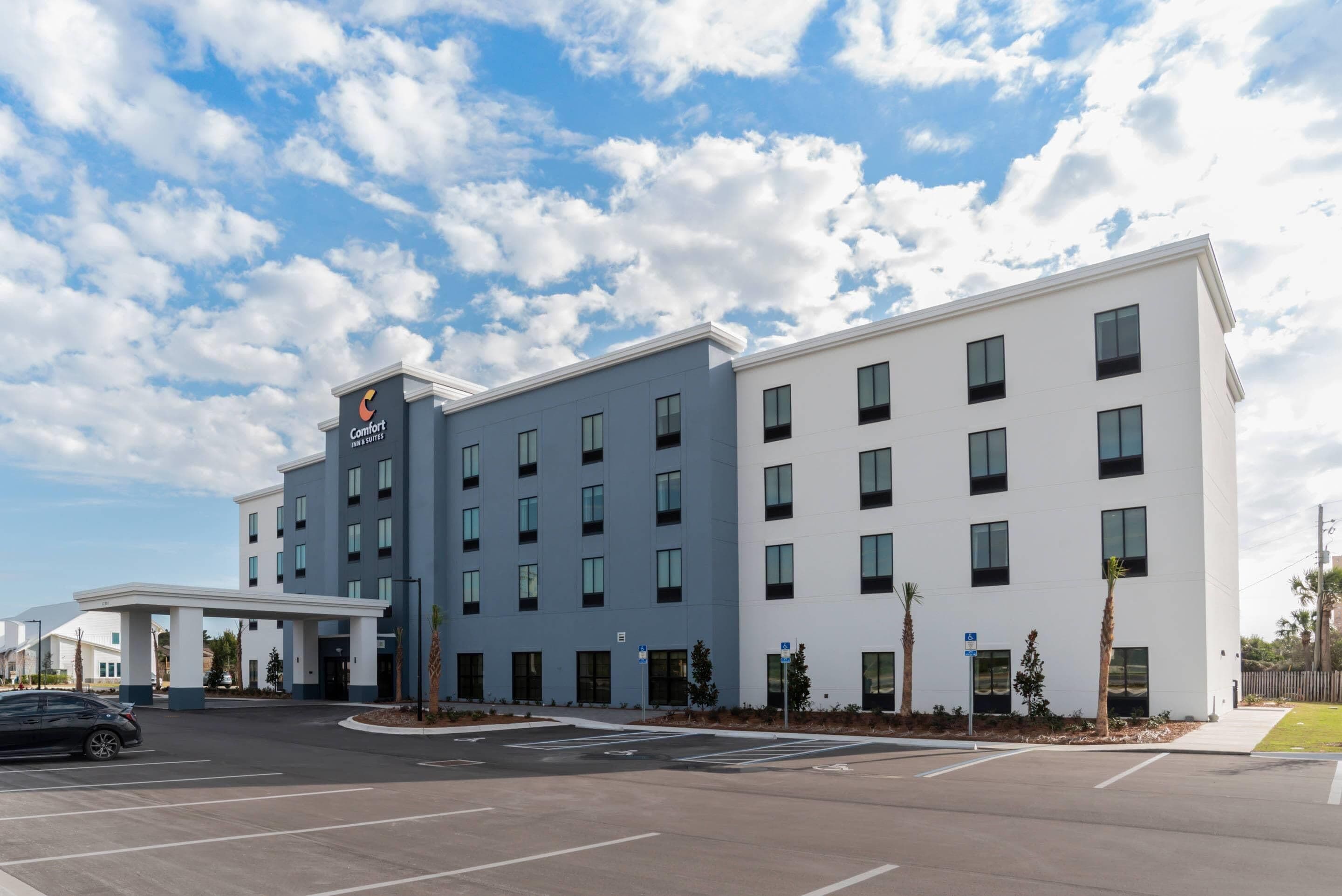 A modern hotel with a flat roof, multiple windows, and a covered entrance.