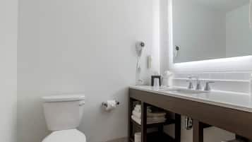 Un bagno moderno con un water bianco, un grande specchio sopra il lavabo e un portasciugamani con asciugamani piegati.