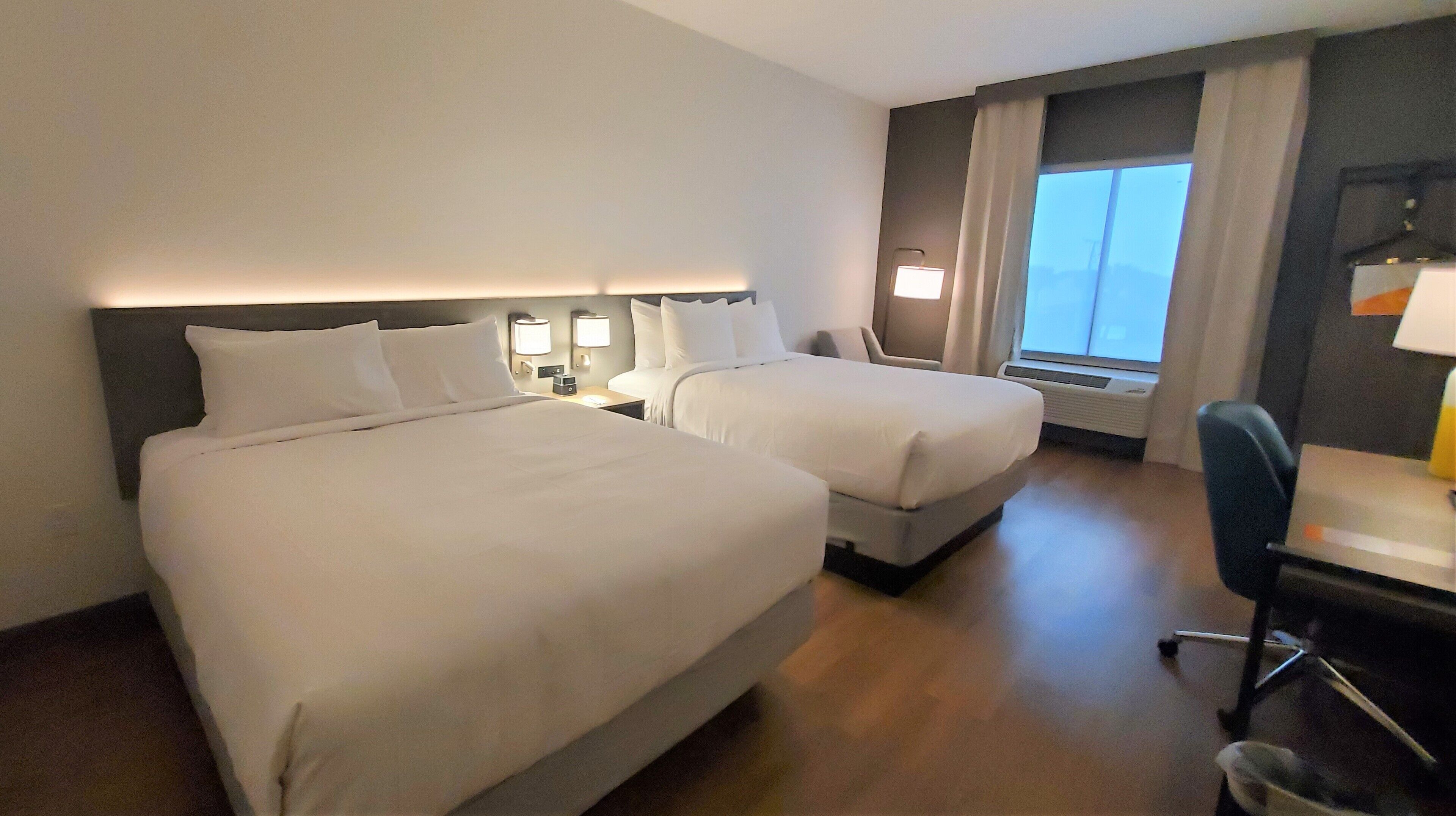 Habitación de hotel con dos camas, un escritorio y una silla.