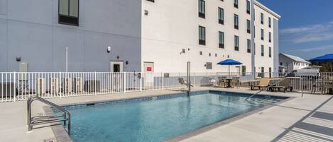 Een buitenzwembad, parasols bij het zwembad en ligstoelen