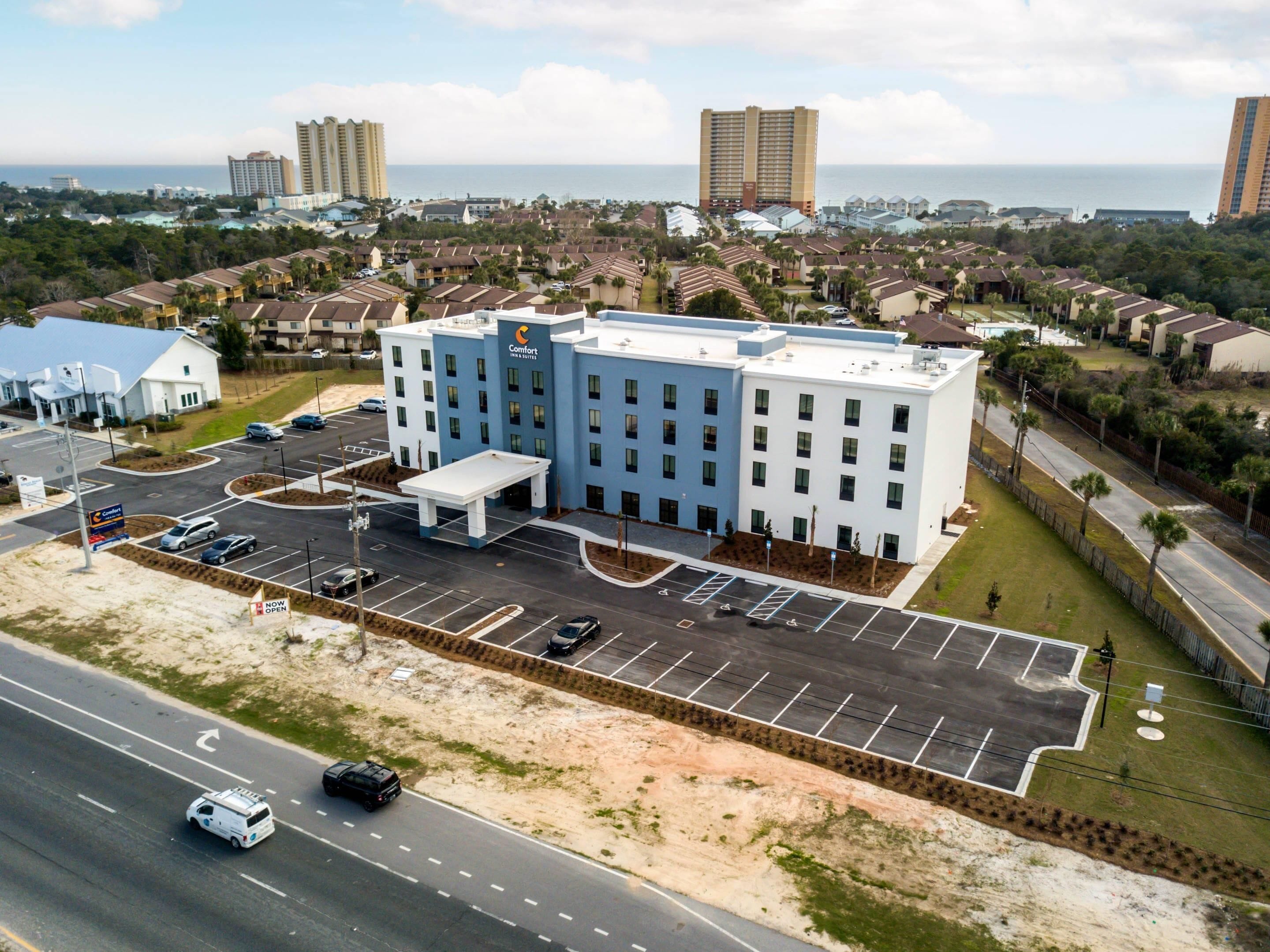 A multi-story hotel with a parking lot and a view of the ocean.
