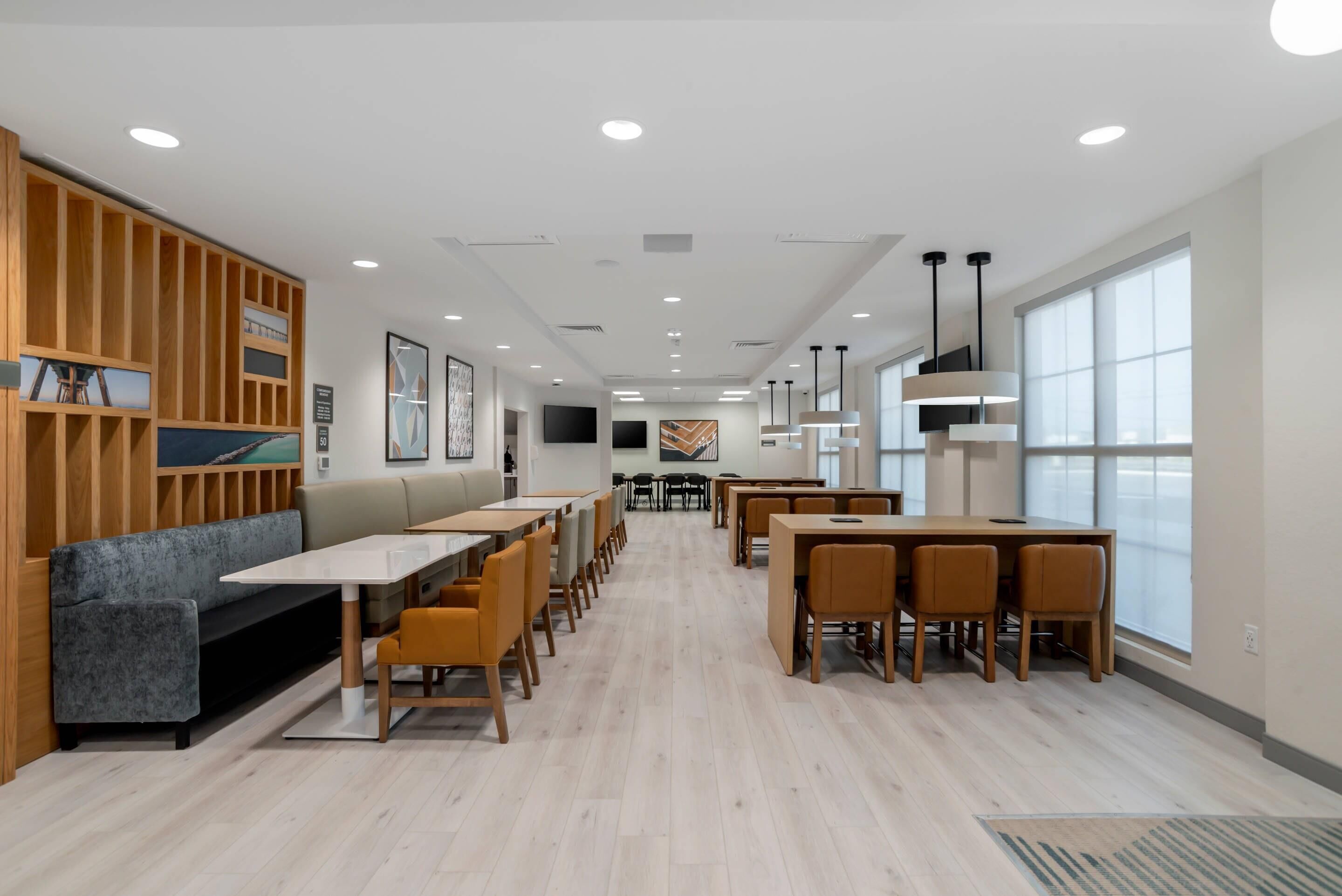 Un comedor moderno con paneles de madera, un sofá y mesas con sillas.