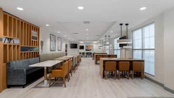 A modern dining area with wooden paneling, a sofa, and tables with chairs.