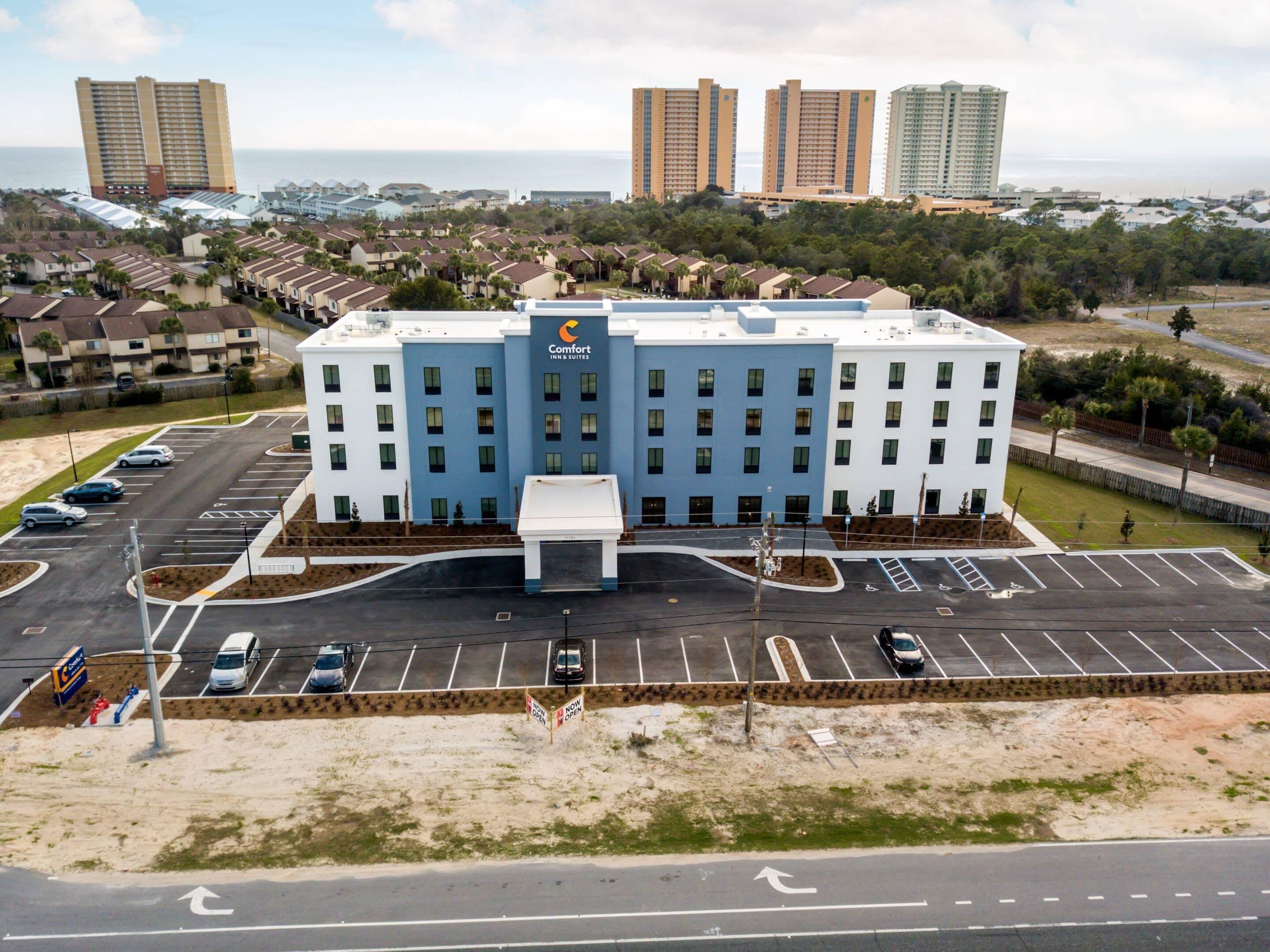 A hotel with a central entrance, parking lot, and surrounding residential area.