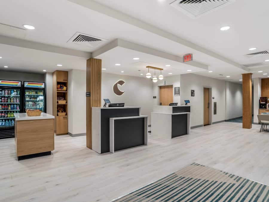 A modern reception area with a counter, a refrigerator stocked with beverages, and a seating area with a table and chairs.