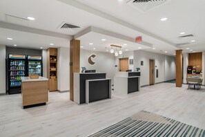 A modern reception area with a counter, a refrigerator stocked with beverages, and a seating area with a table and chairs. - Comfort Inn & Suites Panama City Beach - Pier Park Area (Panama City Beach)