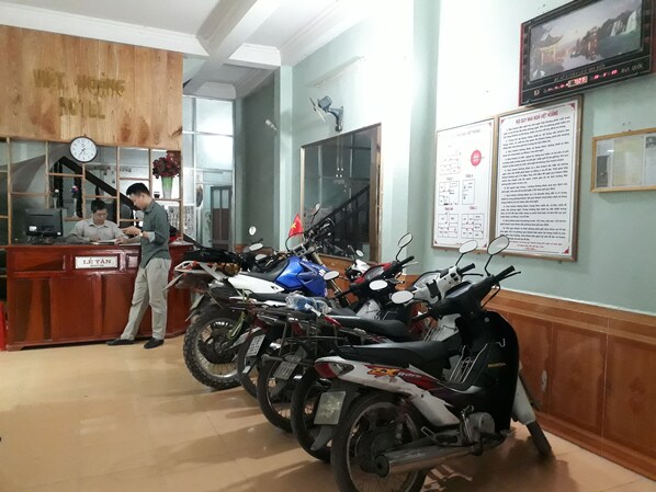 A reception area with a desk, a clock, and several motorcycles parked in the background.