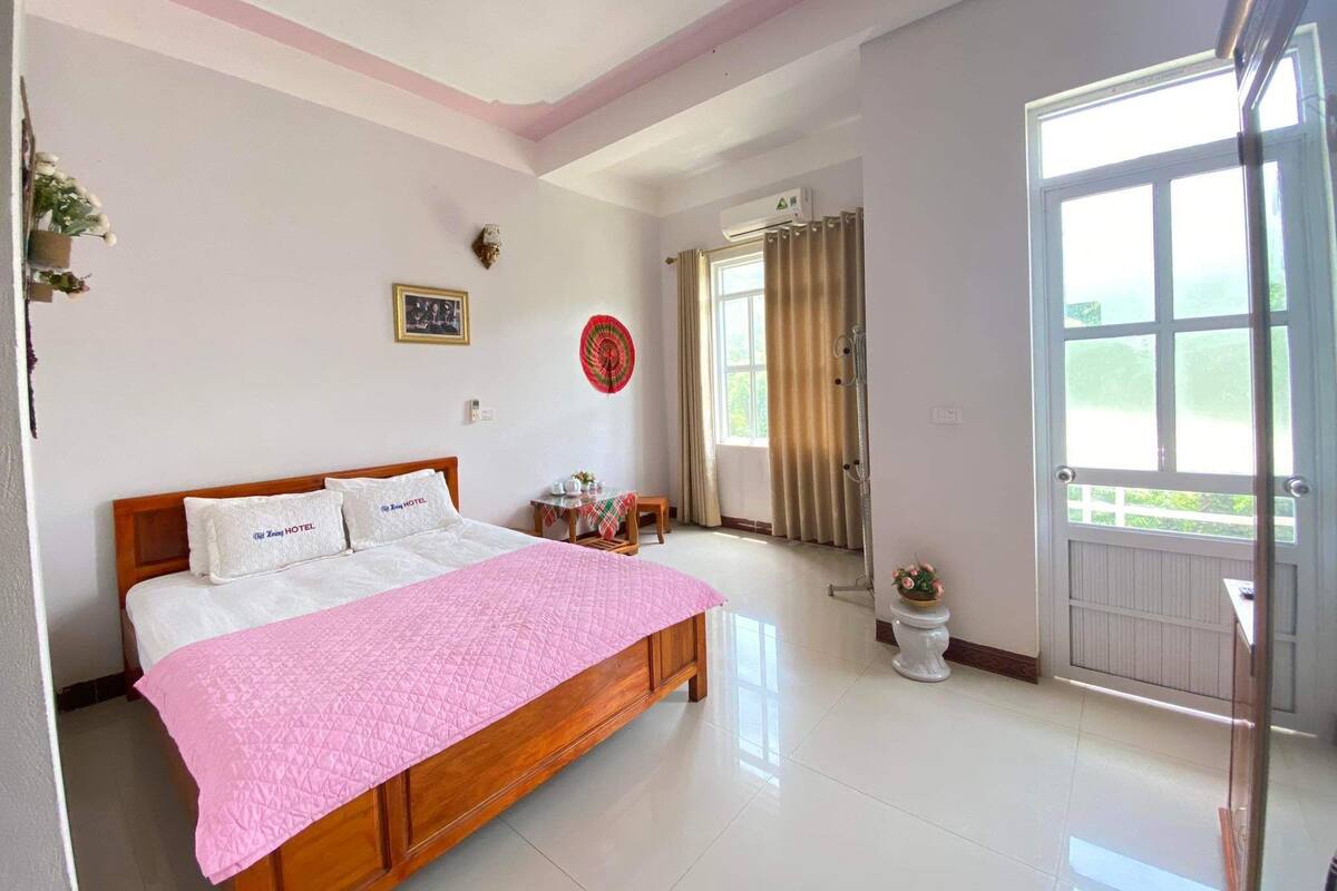 A bedroom with a bed, a bedside table, a window, and a door.