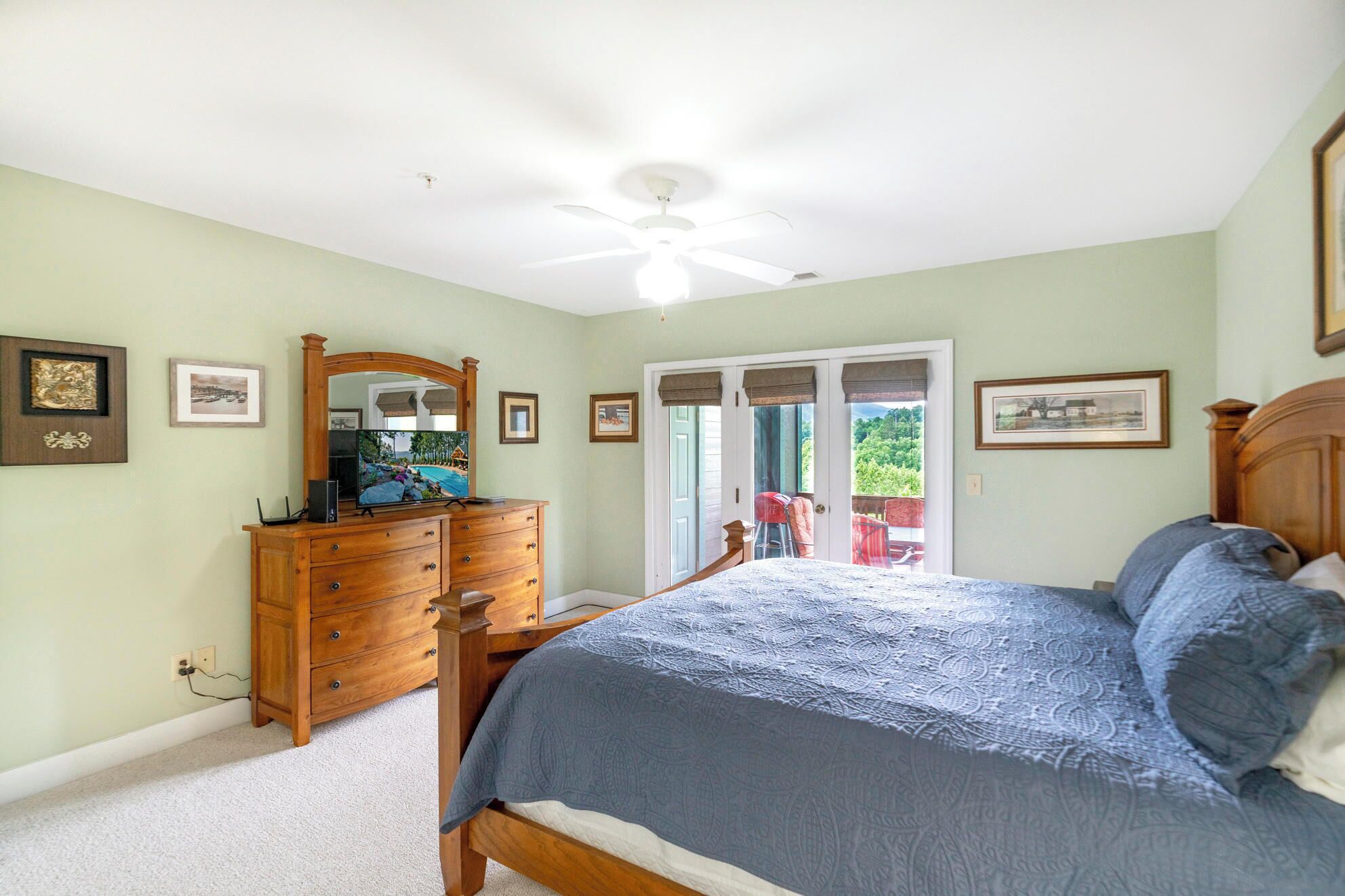A bedroom with a bed, dresser, mirror, and a door leading to a balcony.