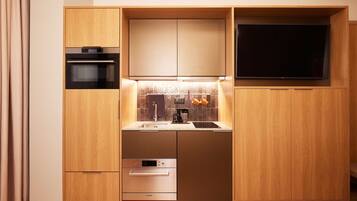 A compact kitchen with built-in appliances, a flat-screen TV, and a small countertop.