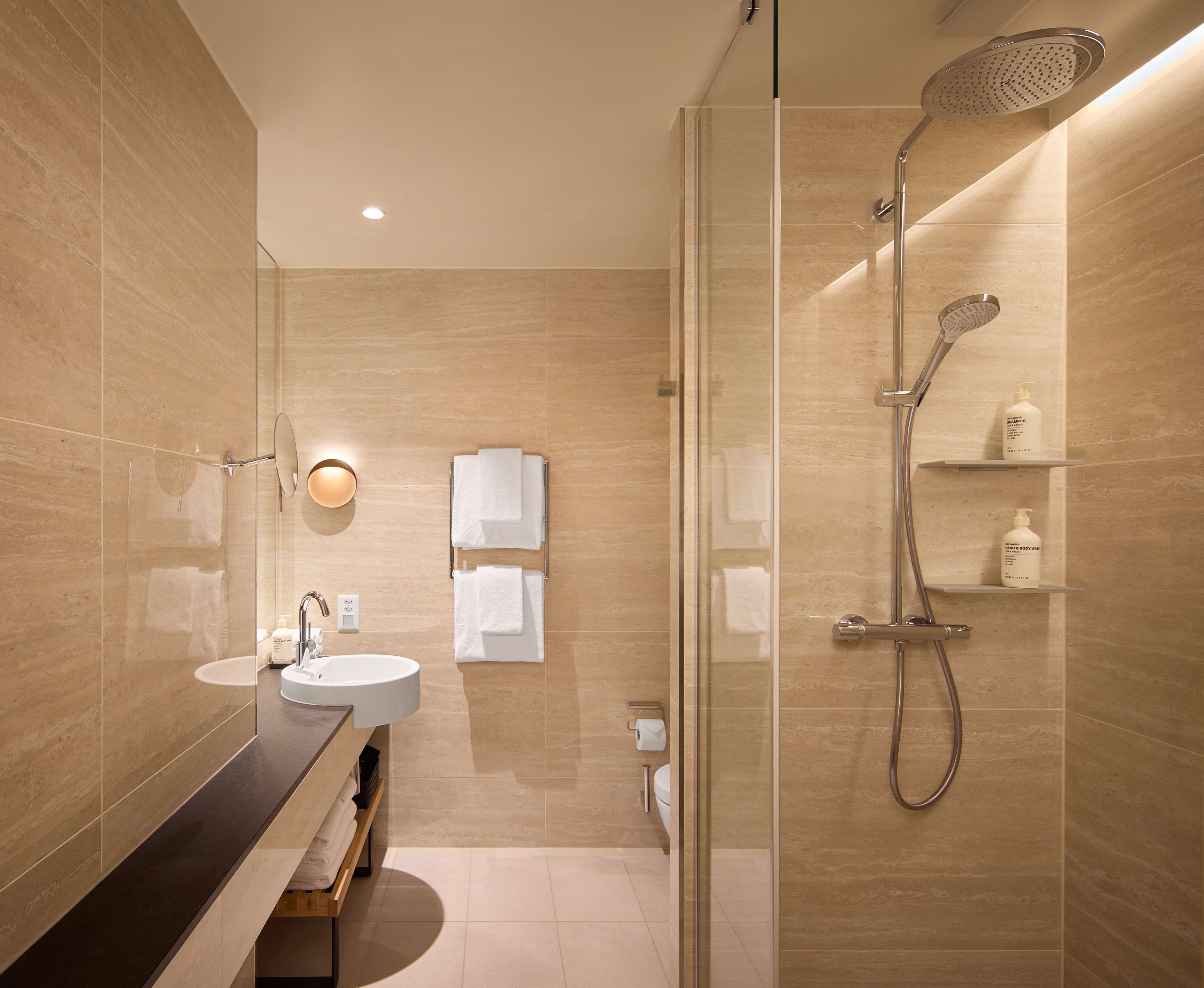 Un bany modern amb dutxa trencada per vidre, un lavabo i un mirall.