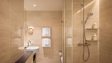 Un bany modern amb dutxa trencada per vidre, un lavabo i un mirall.