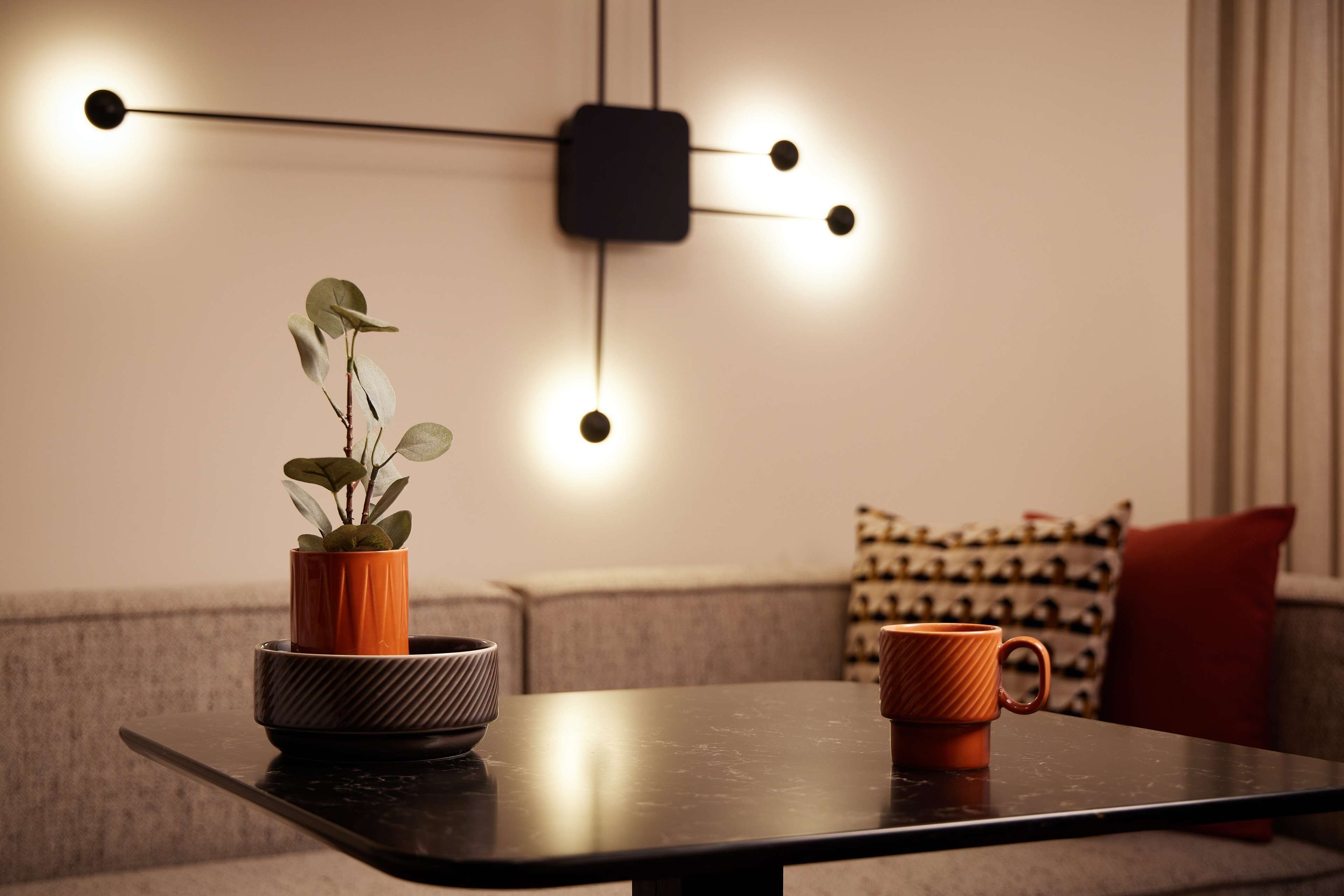 A modern living room with a dark table, a potted plant, and a coffee mug.