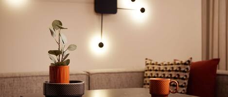A modern living room with a dark table, a potted plant, and a coffee mug.