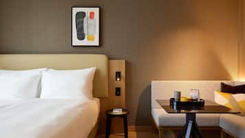 Habitación de hotel con cama, una mesita con bandeja, sofá y una lámpara de pared.