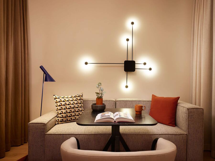 Een gezellige zithoek met een bank, een klein tafeltje, een lamp en een wandlamp.