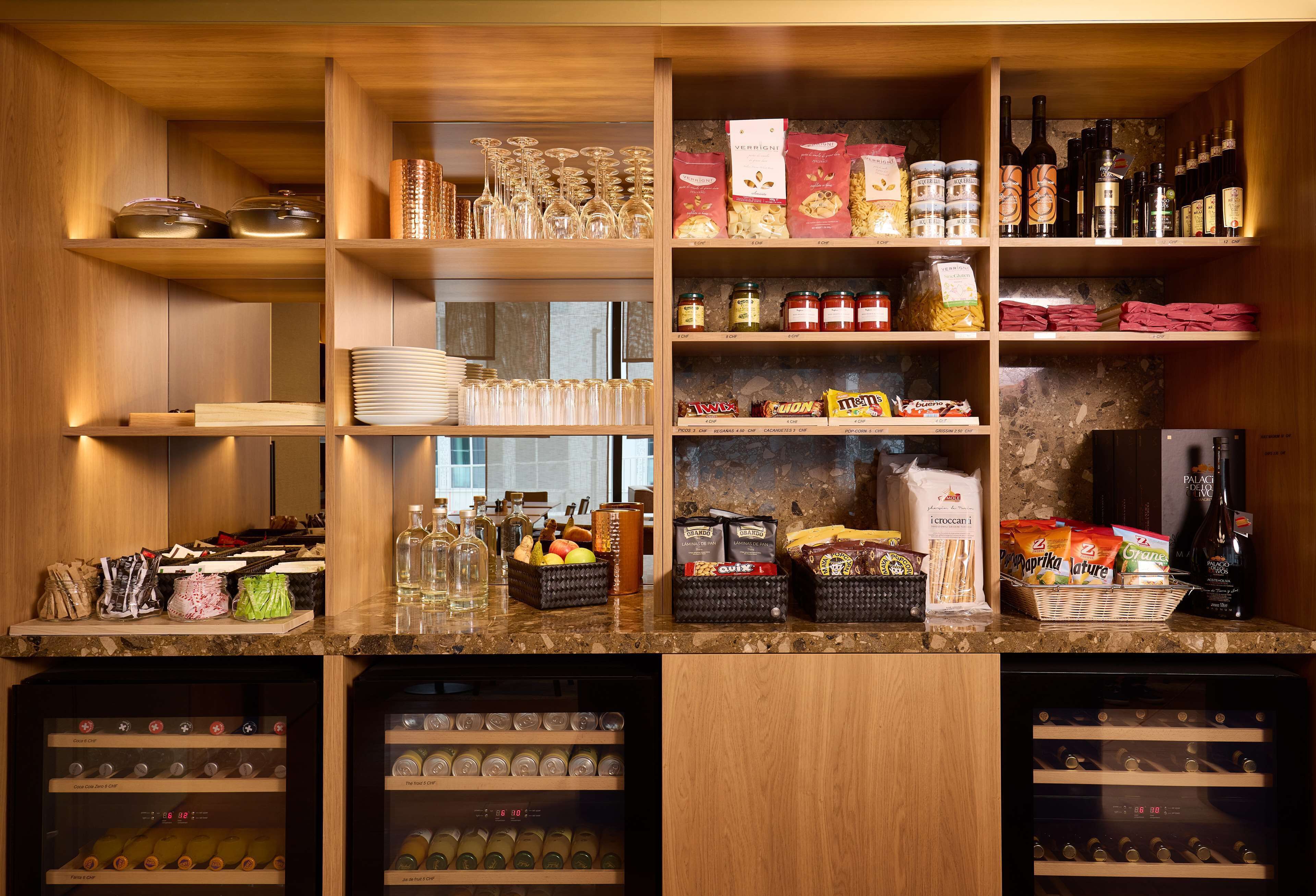 A well-organized bar area with shelves stocked with various bottles, glasses, and condiments.