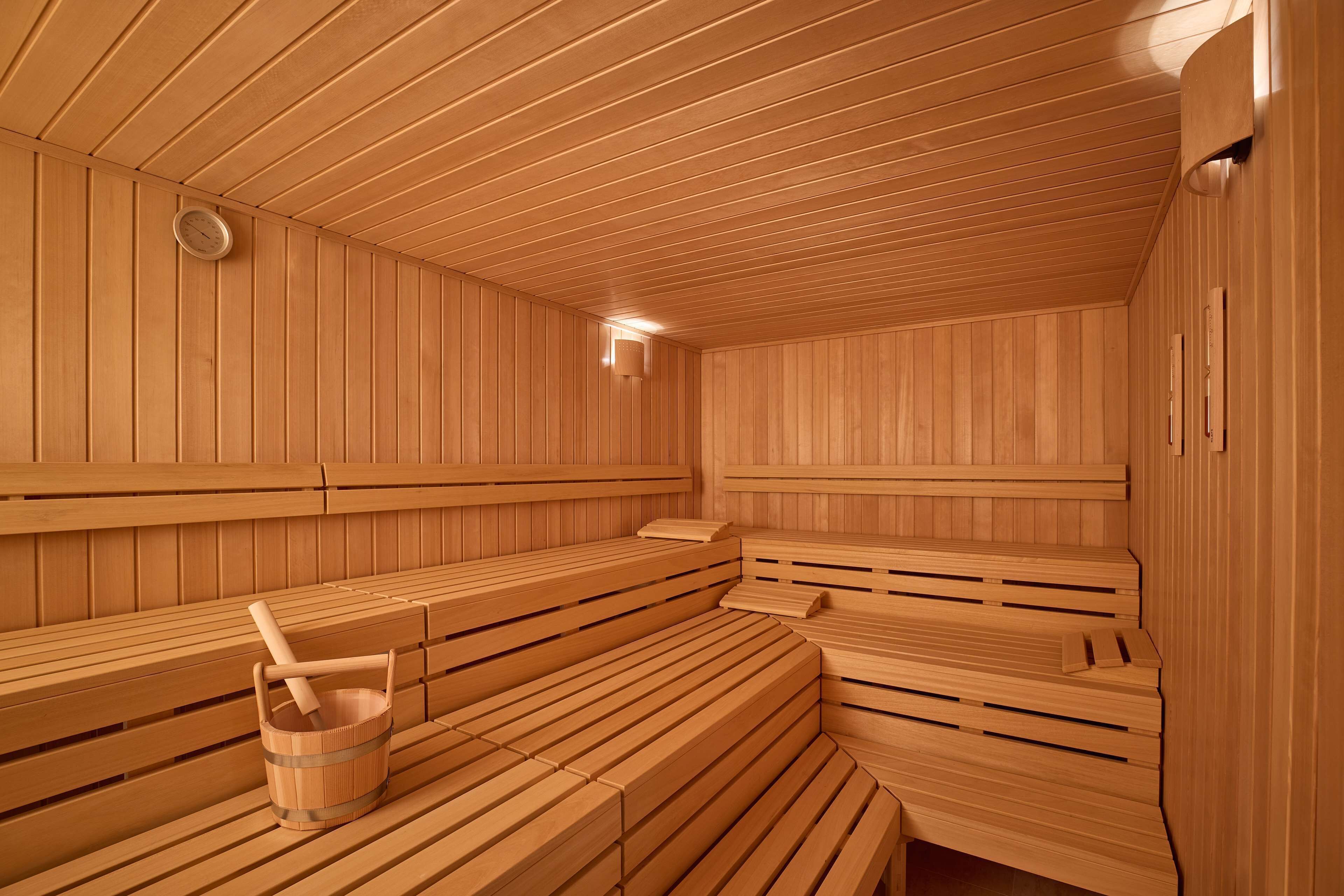 Una sauna con bancos de madera y un balde de madera.