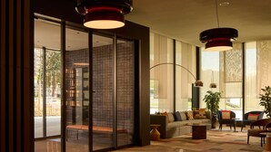 Een moderne lobby met een glazen scheidingswand, een bank en twee hanglampen.