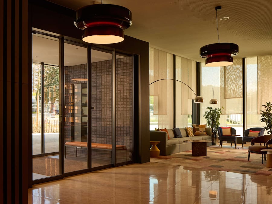 Um hall moderno com divisória de vidro, um sofá e duas luminárias pendentes.