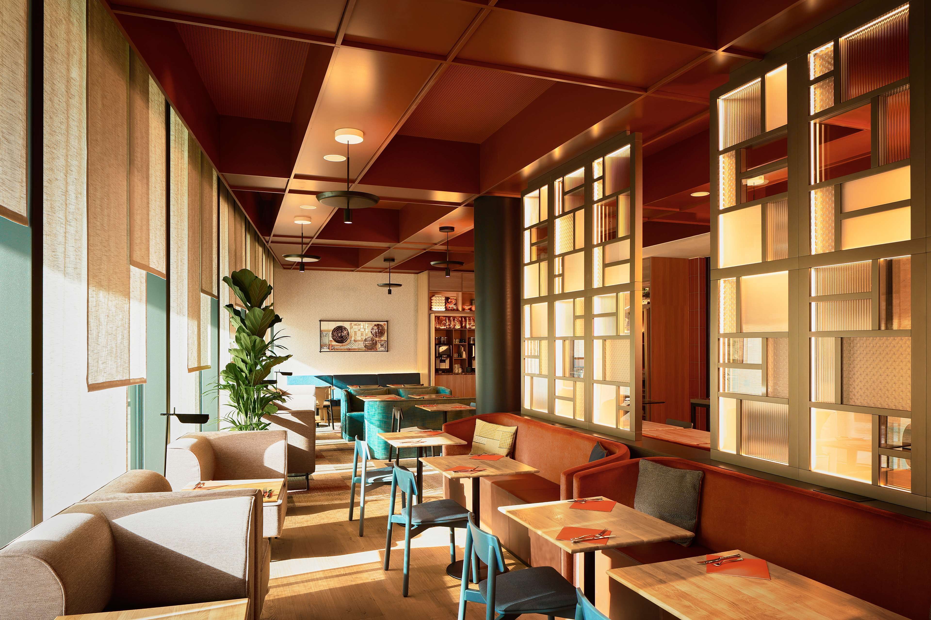A modern interior with seating areas, tables, and a large window with patterned glass.