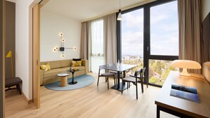 Een moderne hotelkamer met een groot raam, een zithoek, een bank en een lamp.