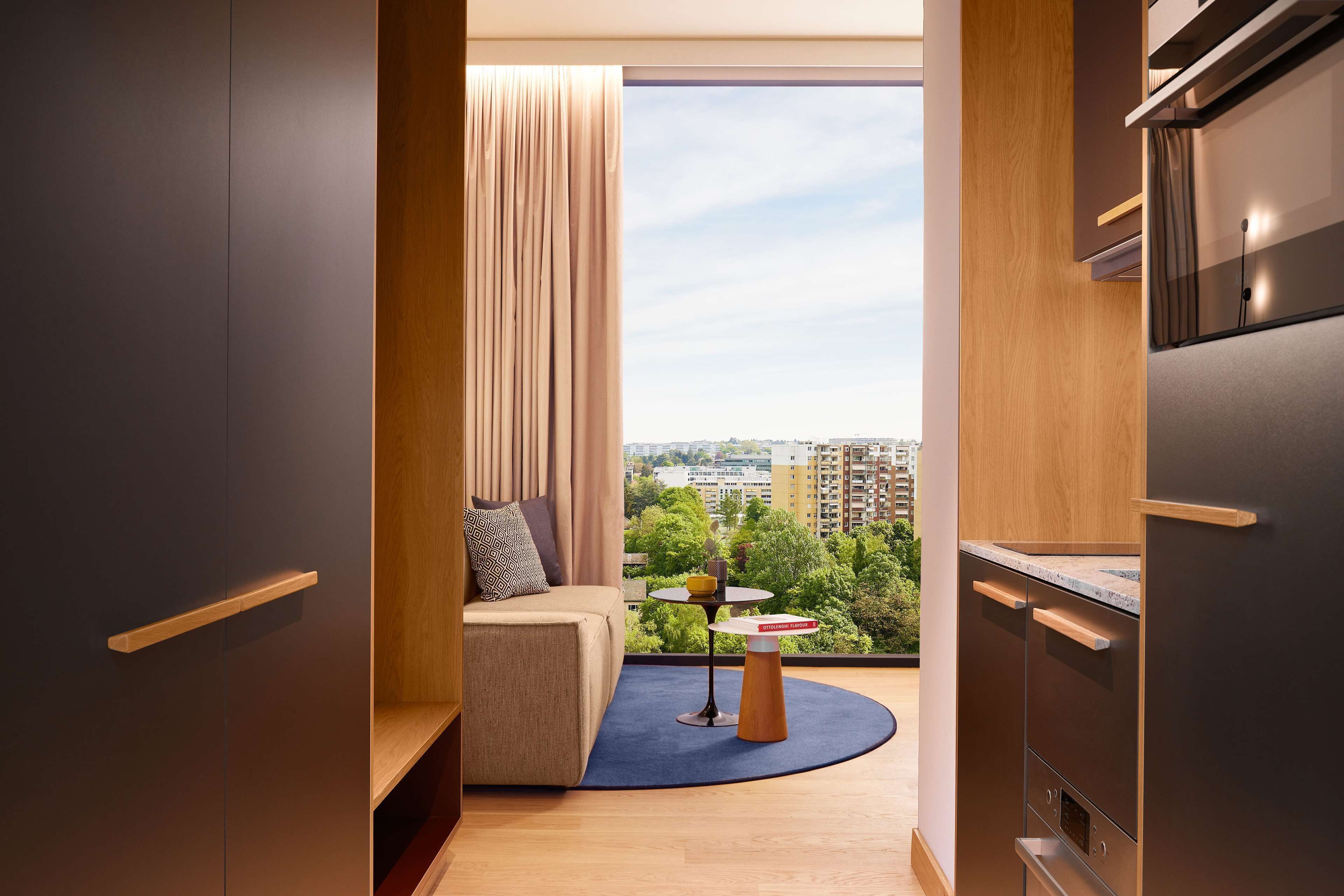 A modern kitchen with a built-in oven and a view of the city through a large window.