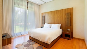 Un dormitorio moderno con una cama grande, cabecera de madera y vistas a zonas verdes.