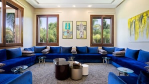 Una sala de estar moderna con un sofá seccional azul, dos mesitas auxiliares y obras de arte en las paredes.