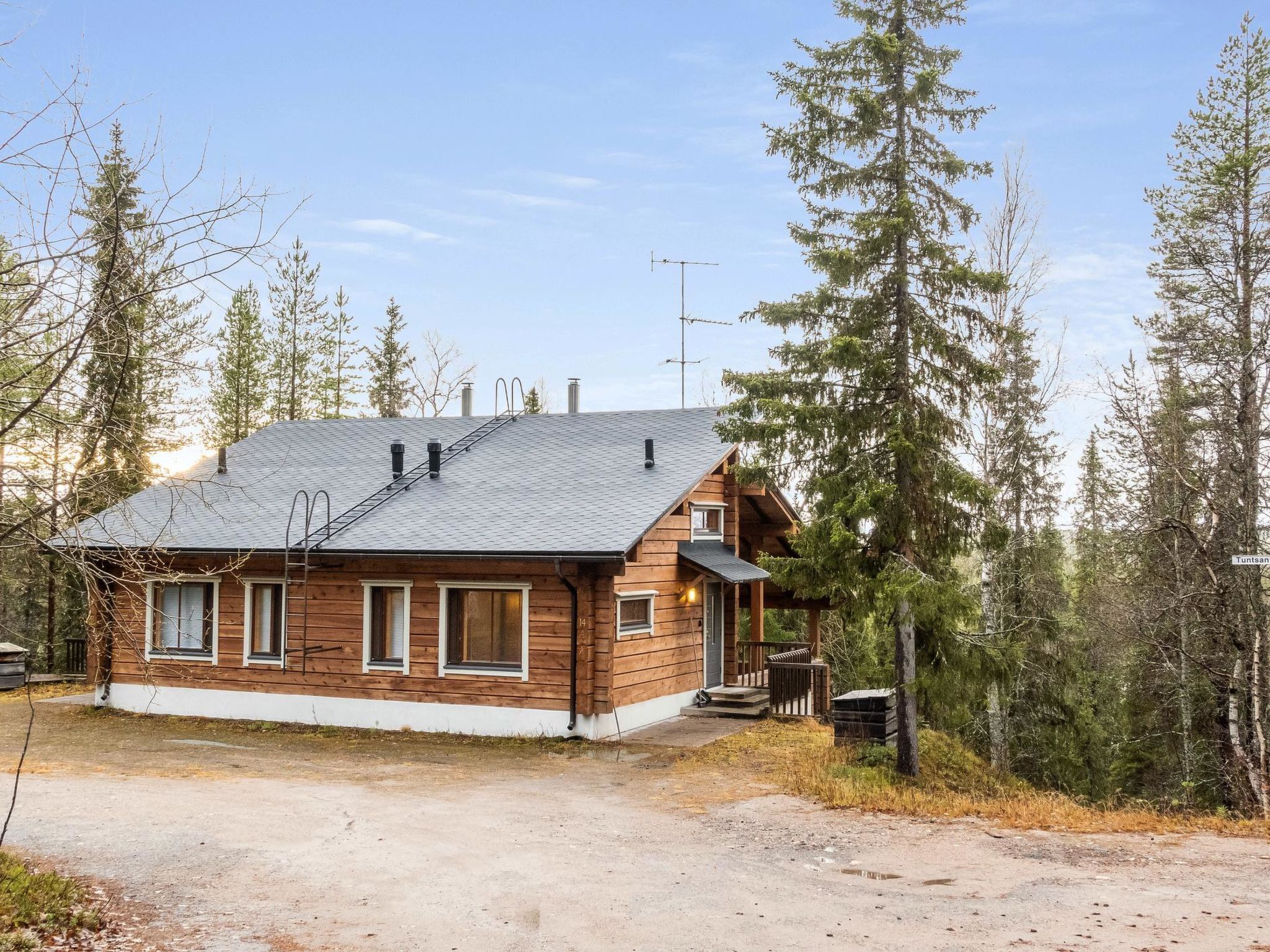 A wooden cabin with a sloped roof, a porch, and a chimney.