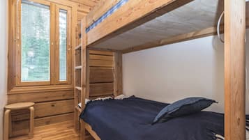 Dormitorio con literas, ventana, un taburete pequeño y una alfombra.