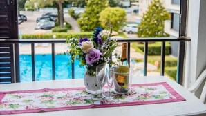 A balcony with a table set for two, a vase of flowers, and a bottle of champagne. - Bilo Standard by Interhome (Marina di Bibbona)