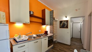 Une cuisine de taille réduite avec des meubles blancs, un plan de travail en granit et un plancher en bois.