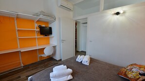 Une chambre d’hôtel avec un lit, une télévision, une armoire et une salle de bain visible à travers une porte ouverte.