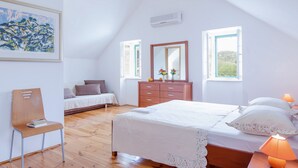 A bedroom with a sloped ceiling, a bed with white bedding, a wooden dresser, a chair, and a painting on the wall. - 3 Bedroom Villa, Private Pool, Brac Island (Sumartin)