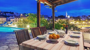 A dining table set for six with a view of a swimming pool and a church in the background. - 3 Bedroom Villa, Private Pool, Brac Island (Sumartin)
