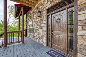 A stone building with a wooden deck, a double door with a metal gate, and a mailbox.