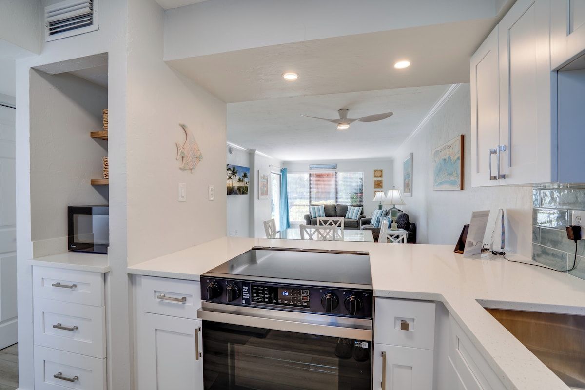 A kitchen with a built-in oven and microwave, white cabinetry, and a dining area with a table and chairs.