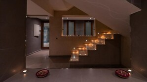 Ein modernes Interieur mit einer von Kerzen beleuchteten Treppe, einem Fenster und einer Tür zu einem weiteren Raum.
